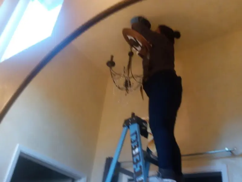 Electrician installing a chandelier in a Wheatfield residence